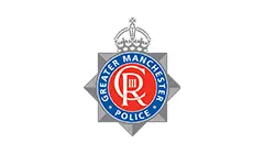 Logo officiel de la police du Grand Manchester, représentant un insigne en forme d'étoile gris argenté avec un emblème circulaire rouge et une couronne.